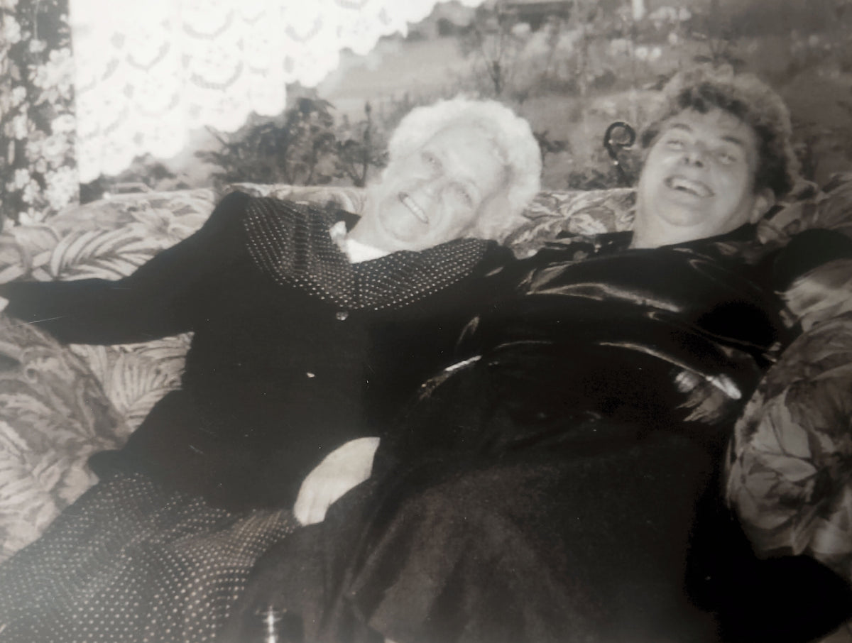 Florence and Amelia laughing together while sitting on a sofa